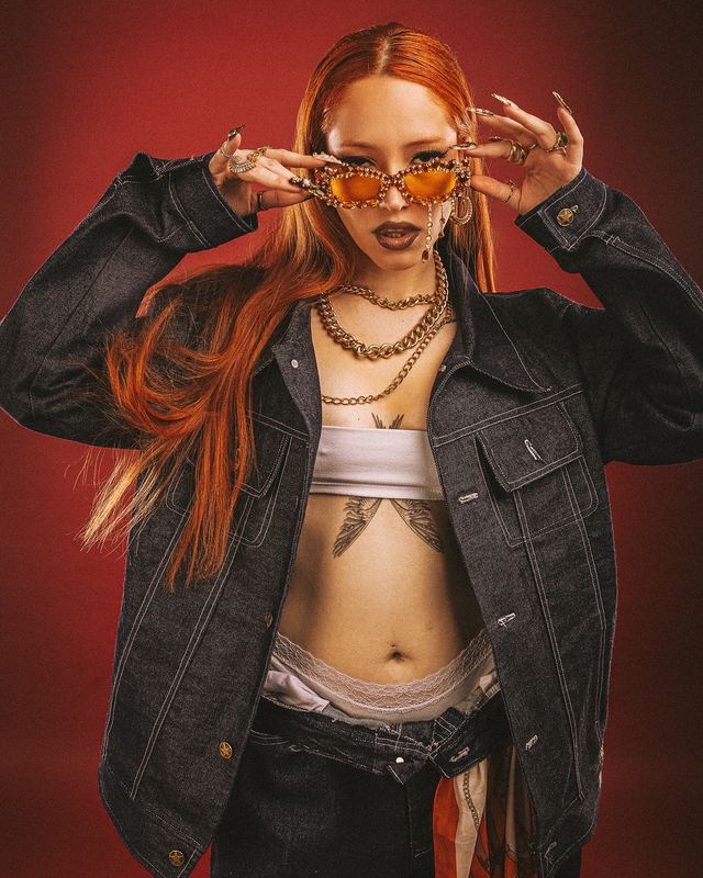 NARA con chaqueta de mezclilla y lentes naranjos